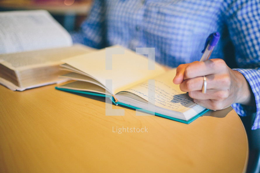 Person studying the bible making notes in a notebook