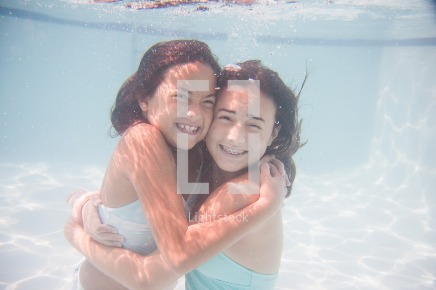 sisters hugging under water 