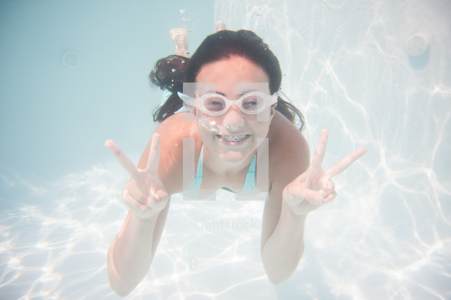 a teen girl under water with goggles 