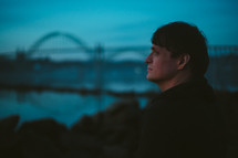side profile of a man and a bridge in the distance 