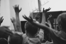 children with raised hands singing to worship music at VBS 