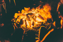 people sitting around a campfire at night 