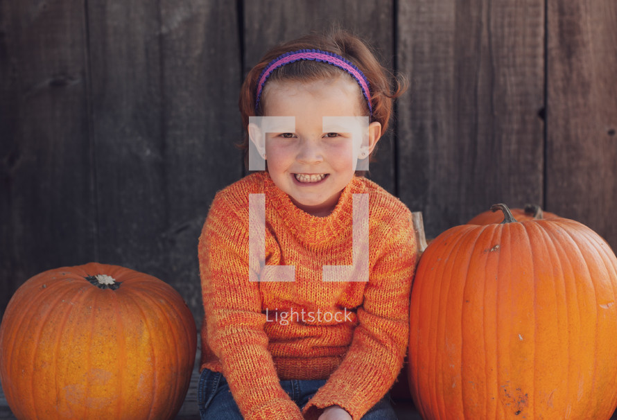 a child sitting with a pumpkin 