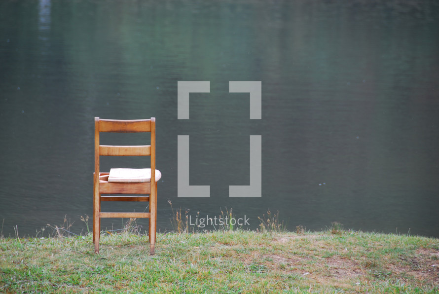 a chair sitting at the edge of a lake 