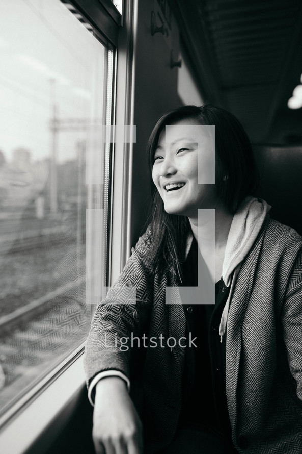 a woman riding on a train looking out a window 