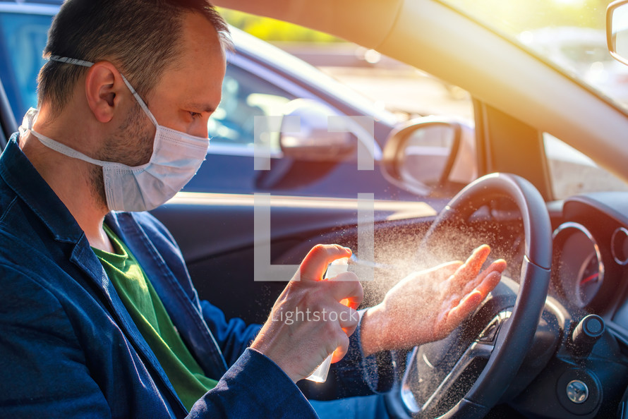 man using hand sanitizer in a car 