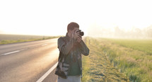 Landscape professional photographer taking a picture near a road with the sunrise in the background