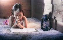 a child reading a Bible and praying 