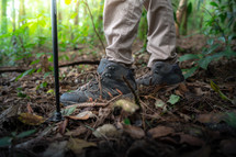 Closeup of male hiker trekking shoes outdoors in forest.