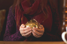 a woman holding a glass Christmas ornament 