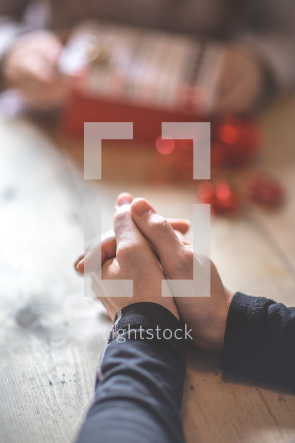 a man with praying hands over a table at Christmas 