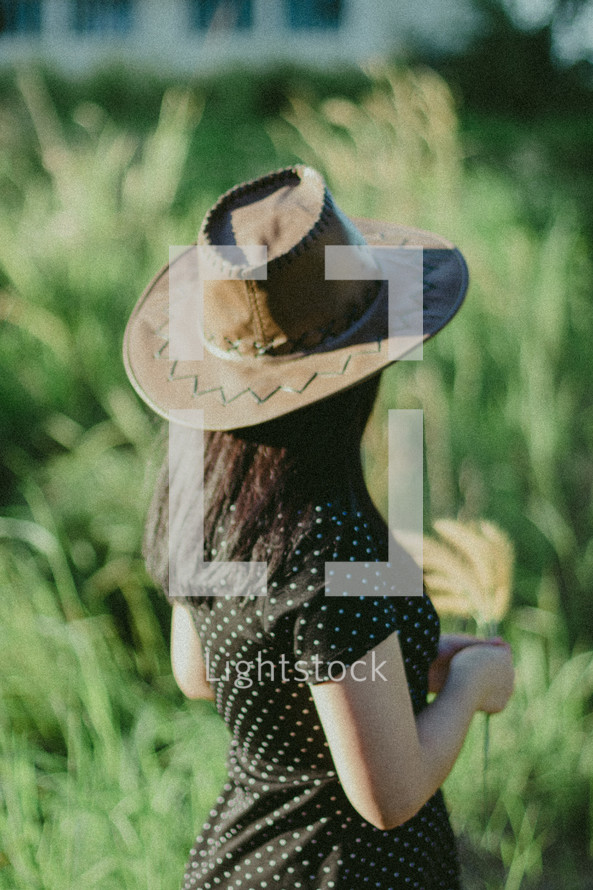 a young woman in a hat standing in a field  