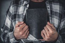 young man hiding a bible in his shirt. 