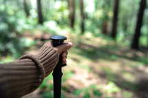 Close up hiking poles in hand of hiker in forest