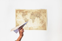 a woman throwing a paper airplane and a map on a wall 