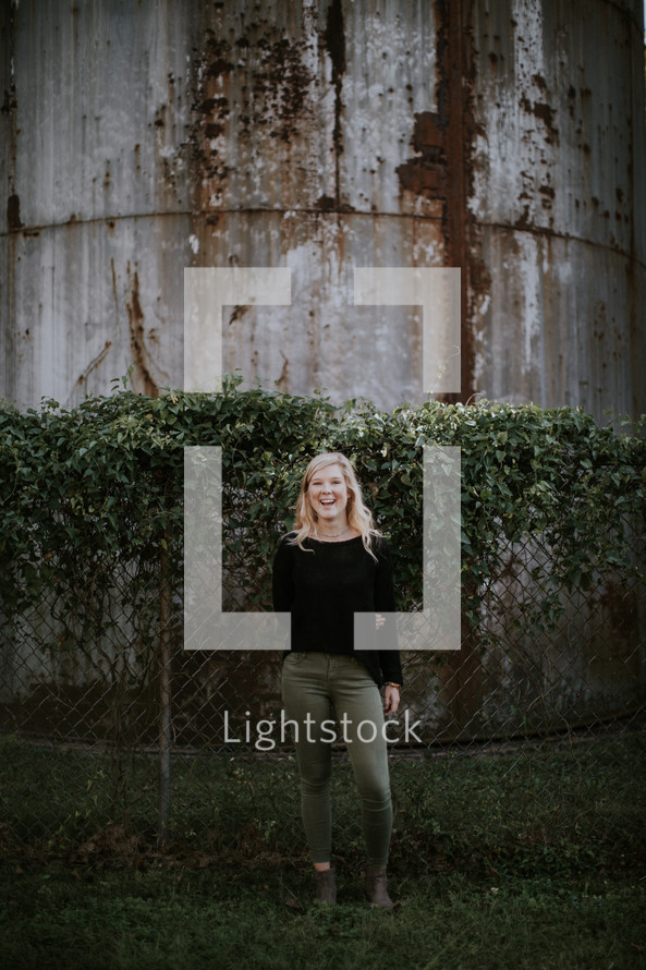 a young woman standing in front of a silo 