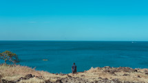 a man standing at the edge of a cliff overlooking the ocean 