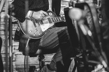 Close up of a man playing electric guitar with the worship team in black and white.