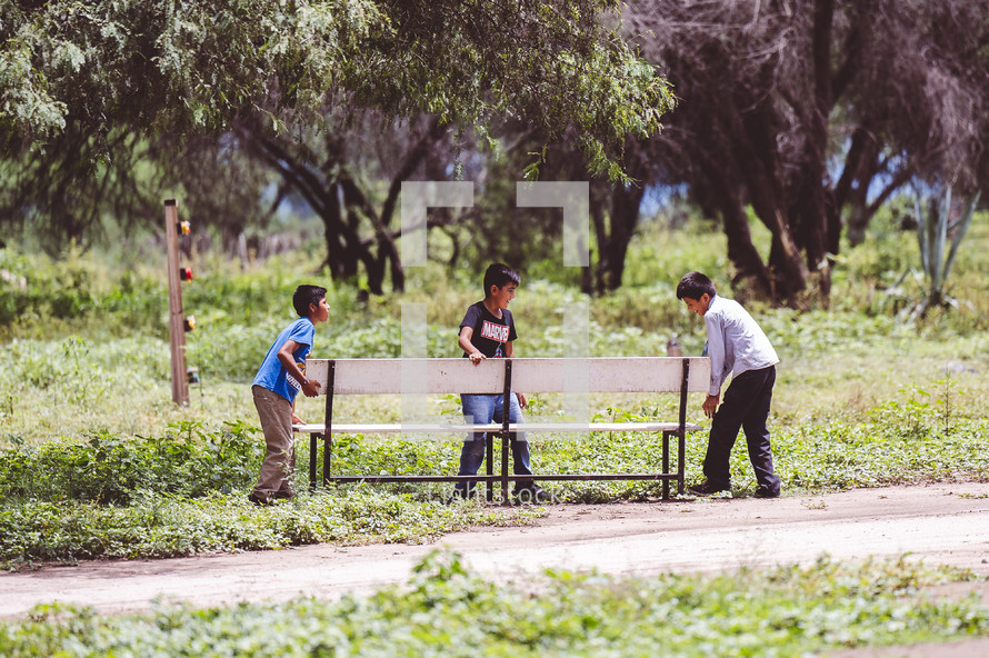 kids moving a bench outdoors in Mexico 