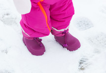 Purple baby snowboots in the fresh snow.