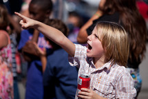 Child pointing and holding a drink