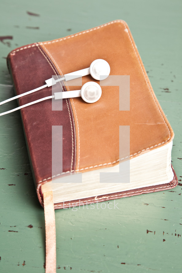 earbuds resting on a Bible
