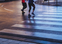 man and woman running across a cross walk