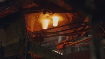 Molten glass pouring out of a Glass melting furnace in a bottle production facility. Glass recycling