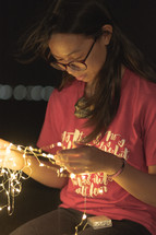 a young woman holding a strand of fairy lights 