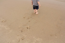 toddler boy barefoot in the sand 