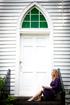 woman sitting on the steps in front of a church 