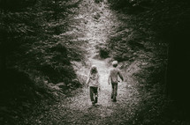 a boy and girl walk along a forest path 