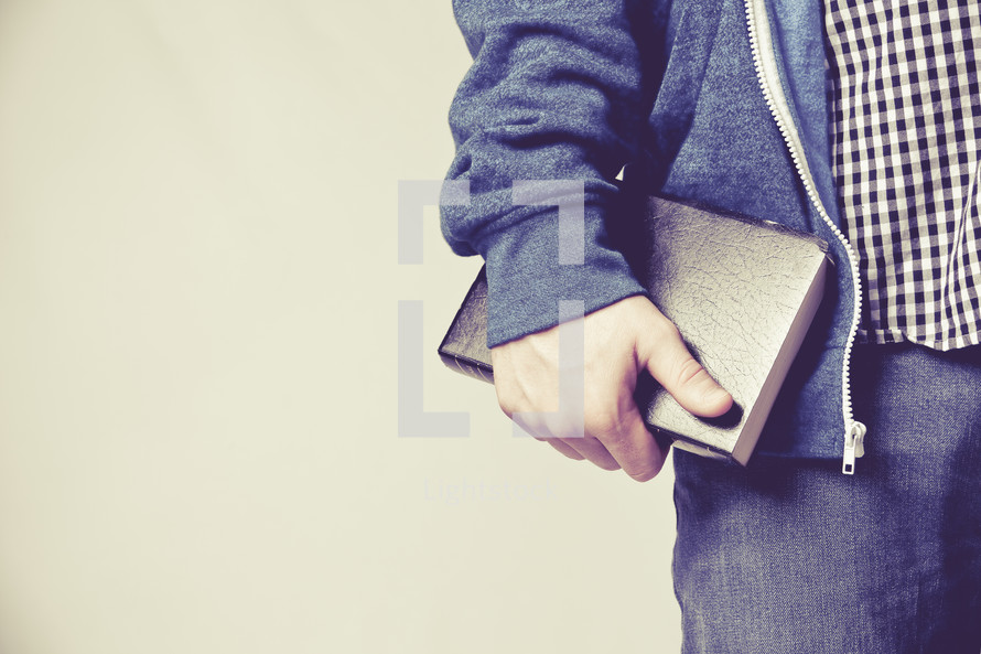 man carrying a Bible against his side