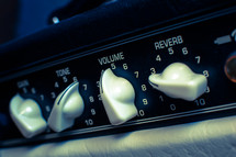 Guitar amplifier level dials: tone, gain, volume & reverb in cross-processed look.