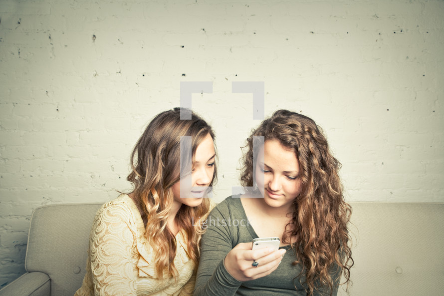two teen girls looking at their cellphone