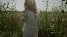 girl walking through a field of tall grasses