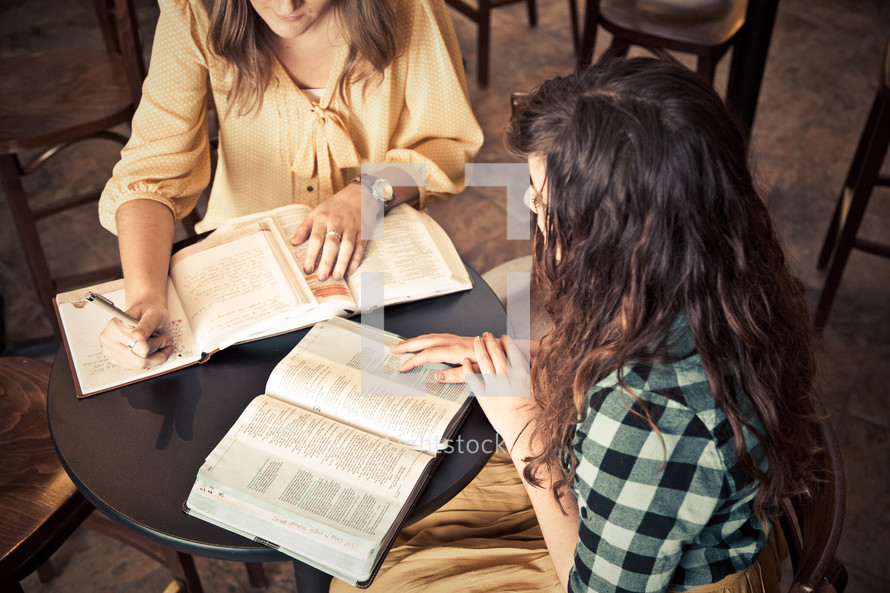 young women sitting at a table in front of Bibles and journals at a Bible study