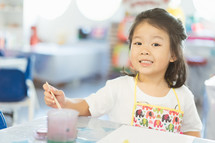 toddler in an apron painting 