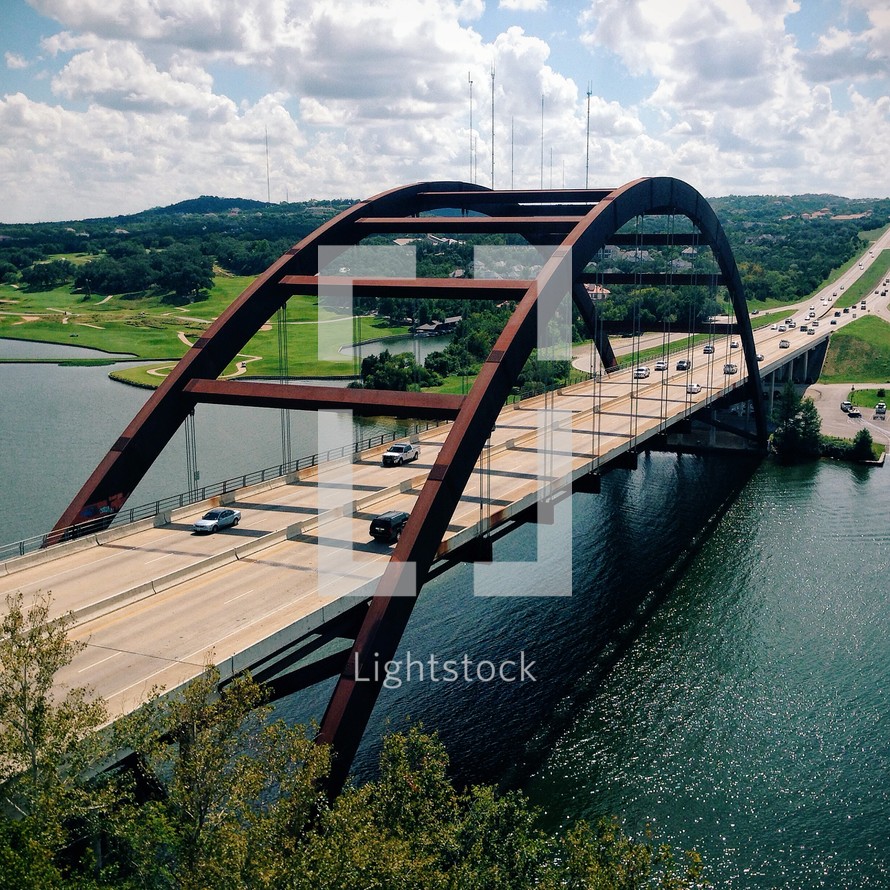 Cars passing over a bridge over a river. 
