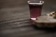 Communion bread and wine on a wood surface.