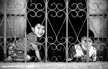 Boys playing behind chain window/fence