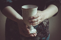 A woman holding a cup of communion wine.