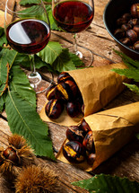 Roasted chestnuts in paper cones on wooden table.