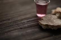 Communion bread and wine on a wood surface.