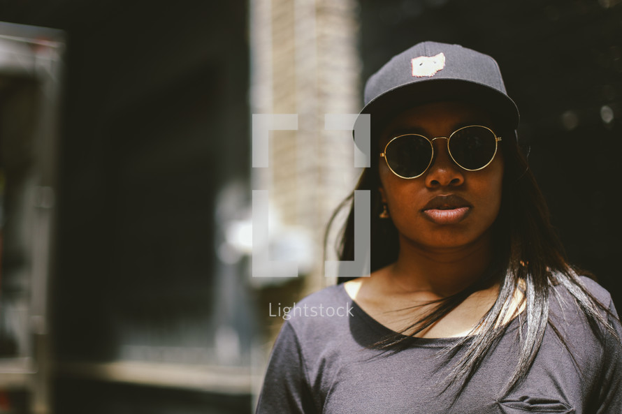 head shot of an African American woman in sunglasses and a ball cap 