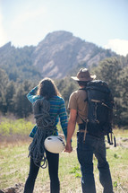 a couple holding hands outdoors while backpacking 