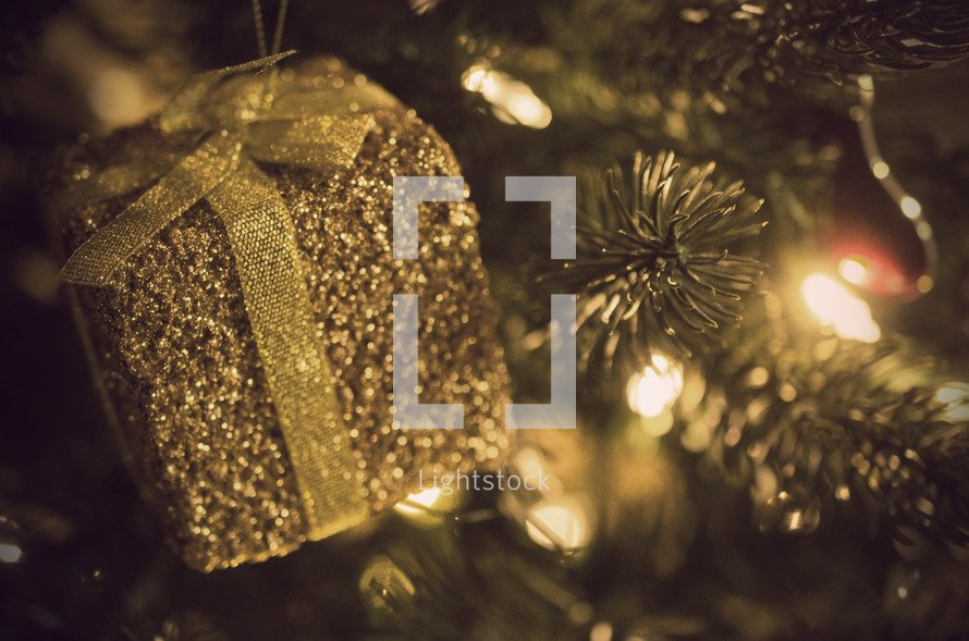 gold present ornament hanging on a Christmas tree