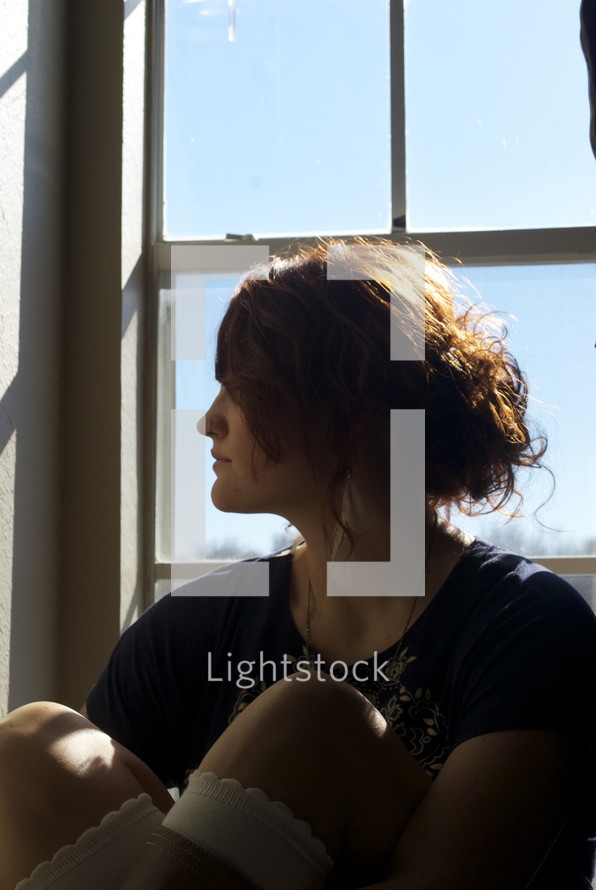 profile of a woman sitting in a a window