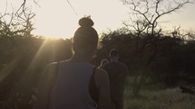 people walking through a field at sunset 