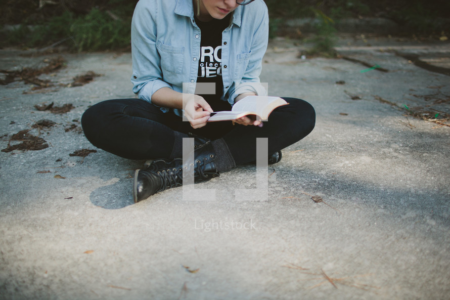 Teen reading Bible outdoors